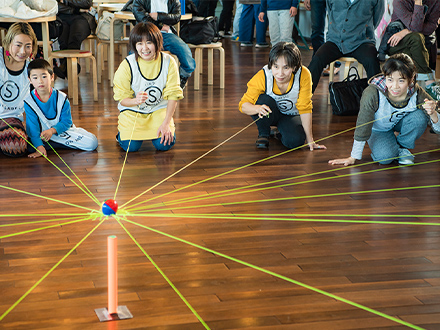 【写真5】最後の締めの「ソレイユ」。房のように繋がったロープの端を、全員が一本ずつ放射線状に広がって持ち、その中心に置かれたボールをゴールの台に運ぶ。