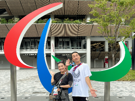 【写真1】認定NPO法人スローレーベル　理事長　栗栖良依さん、スローサーカス ディレクター　金井ケイスケさんとのツーショット　パラリンピック会場にて