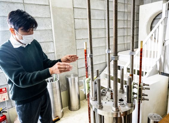 磁場が発生するパルスマグネット部分の解説をする小濱氏。